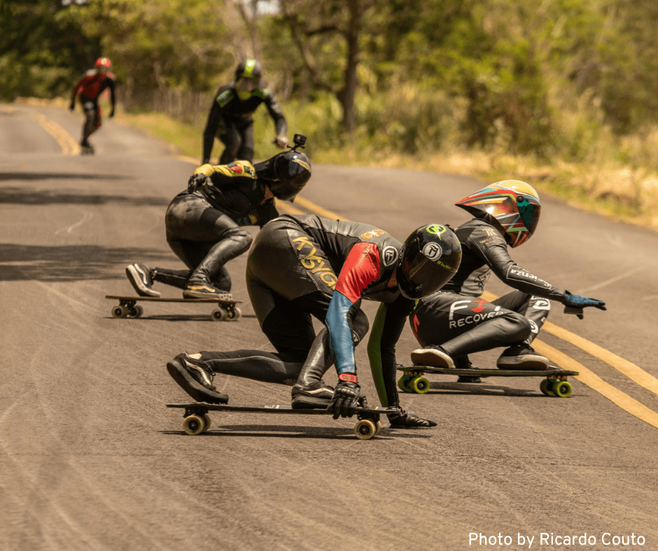 A group of competitors skateboarding downhill on a road, showcasing their skills and speed.