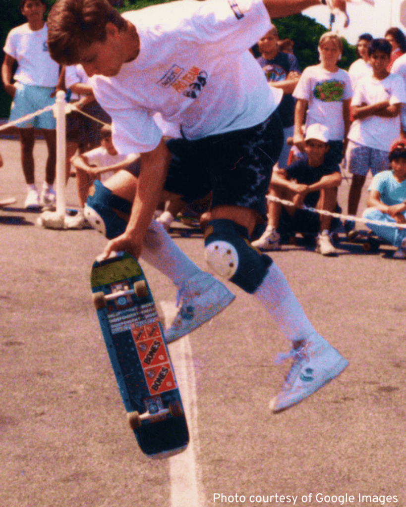A skilled skateboarder, Rodney Mullen, executes a trick while a captivated audience watches in awe
