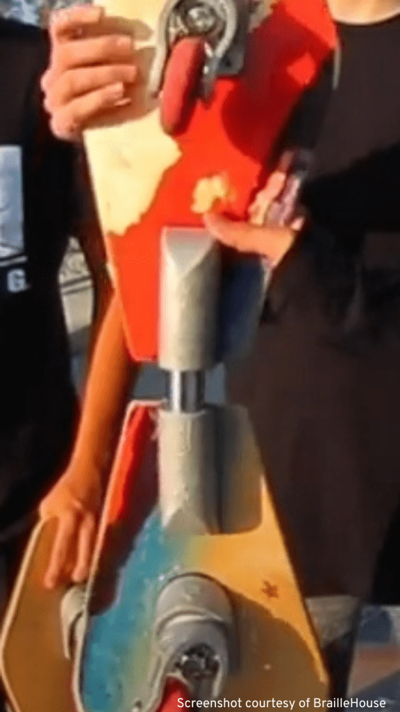 Skateboarder proudly holds a colorful red, blue, and yellow skateboard, showcasing their gear as a top casterboard rider.