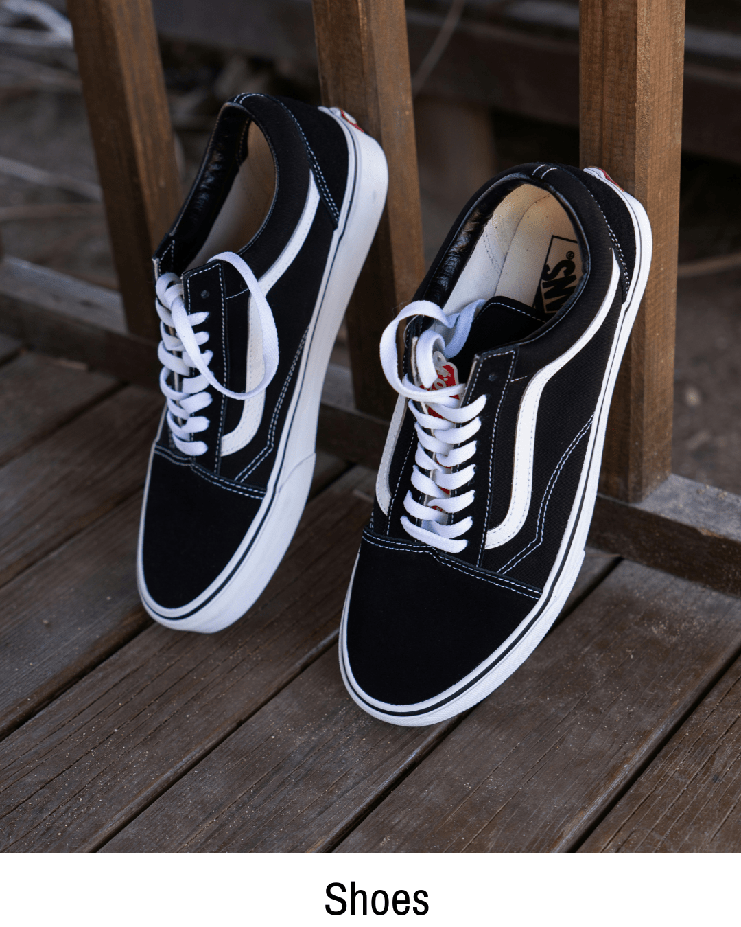 Black and white Vans shoes displayed on a wooden bench, part of the shoe hub page at skatershomebase.com.