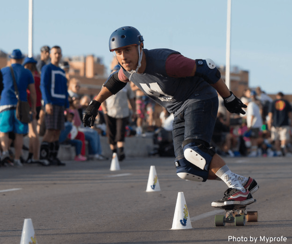 A man navigates a slalom course on his skateboard during a competition.