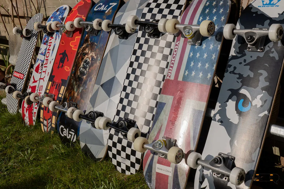 A row of colorful Walmart skateboards lined up neatly on green grass, showcasing options for skaters from skatershomebase.com.