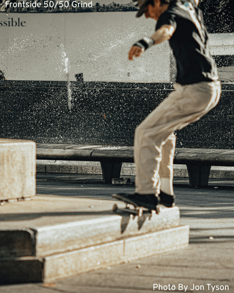 A rad skater executes a frontside 50/50 grind on a ledge in the street, showcasing his skateboarding skills.