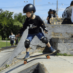 A young child rides a skateboard down a ramp, demonstrating enthusiasm for skateboarding as a beginner.